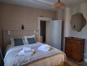A bedroom with a bed, a wooden dresser, a mirror, and a door leading to another room. - L'Entre-Deux Eaux Family Home - 5 minutes from Le Pal (Diou)