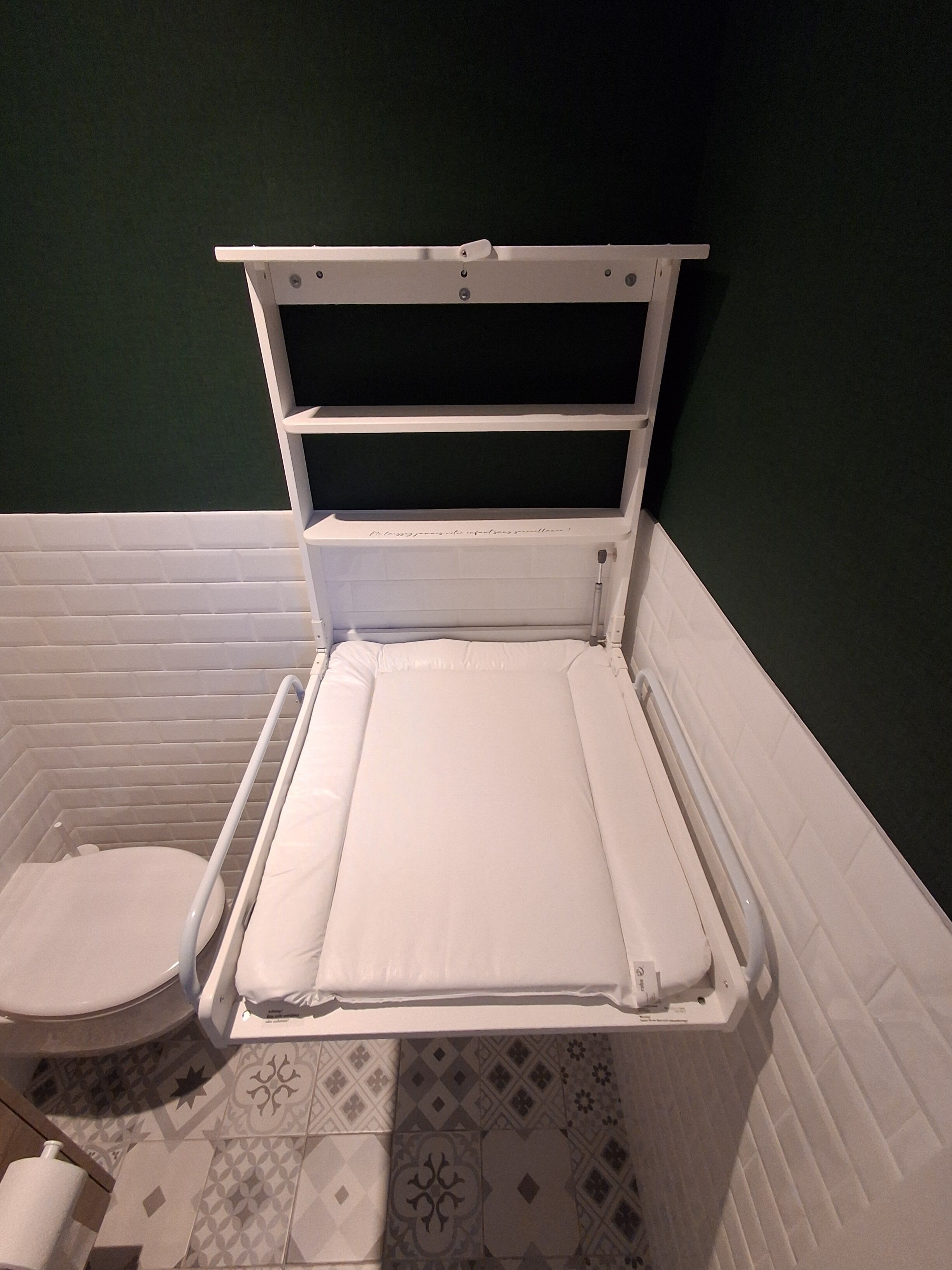 A bathroom with a white bathtub, a toilet, and patterned floor tiles.