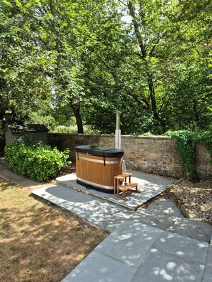 A hot tub in a garden with a brick wall and greenery. - Ware Lodge at Woodhall Park | Sleeps 3 (Hetford)