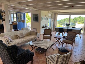 A spacious living area with a sofa, chairs, a coffee table, and a dining table. - House for rent, 5 minutes from the beach, Samzun, Belle-Île-en-Mer (Locmaria)
