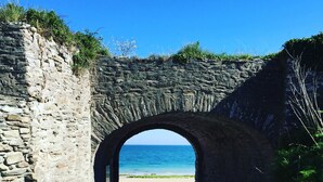 Een stenen bogenpoort die naar een strand leidt.