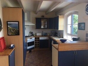 Eine Küche mit dunklen Schränken, einer Holz Arbeitsplatte und einem Fenster, das für natürliches Licht sorgt.