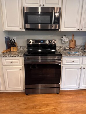 A kitchen with white cabinets, a stainless steel microwave, and a black oven. - Family-Friendly Bradenton Retreat with Private Pool (Bradenton)