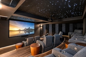 Cine en casa con techo estrellado, pantalla grande y asientos cómodos.