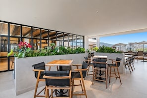 A modern outdoor seating area with tables and chairs, surrounded by greenery and overlooking a cityscape. - Luxury Studio at Valarte with Resort Amenities in Prime Puerto Vallarta Location (Puerto Vallarta)