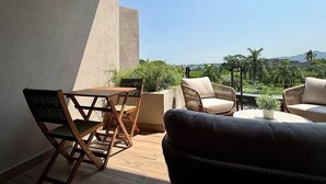 Un balcon avec une table et des chaises, un canapé et une plante en pot.