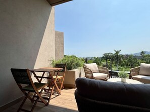 Ein Balkon mit Tisch, Stühlen, einer Couch und einem Blumentopf.