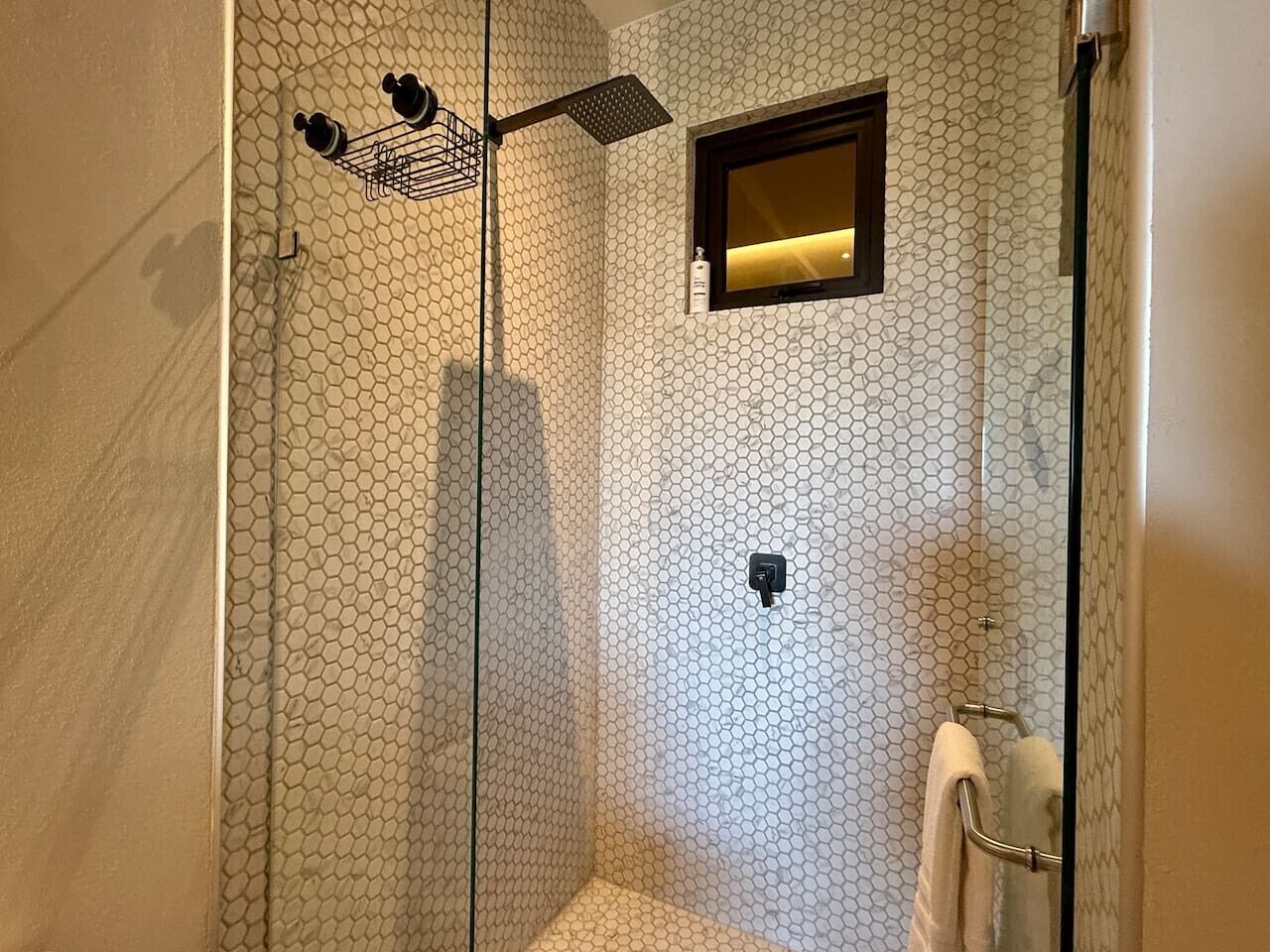 Eine Dusche mit Glastür, einem kleinen Spiegel und einem Handtuchhalter.