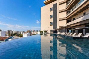 A rooftop infinity pool with lounge chairs and a cityscape view. - Luxury Studio at Valarte with Resort Amenities in Prime Puerto Vallarta Location (Puerto Vallarta)
