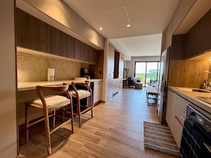 Una cocina moderna con armarios de madera, un comedor con taburetes y vistas a un salón de comedor.