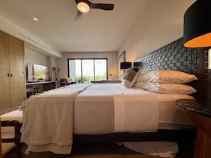 Un dormitorio moderno con una cama grande, un ventilador de techo y un televisor sobre un mueble.