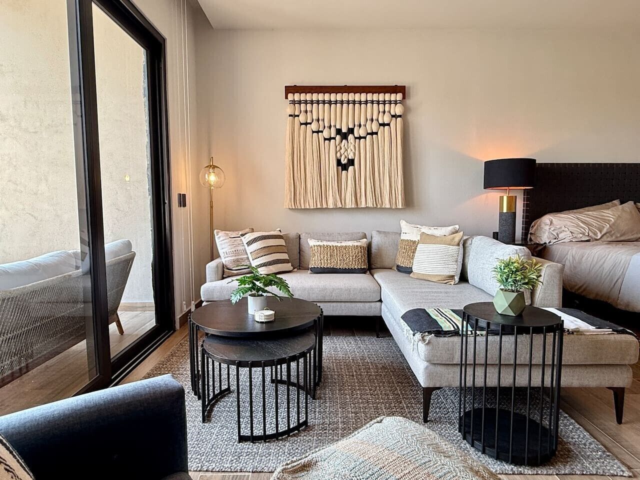 Un salon moderne avec un canapé, deux tables rondes et un élément décoratif mural.