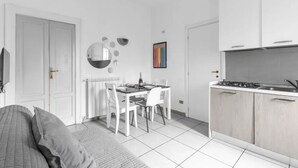 Een ruimtelijk ingerichte leefruimte met een eethoek, kitchenette en een bed.