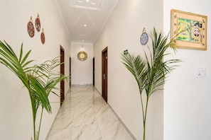 A hallway with a marble floor, doors on both sides, and decorative wall hangings. - Collection O Salasar Balaji Temple (Sujangarh)