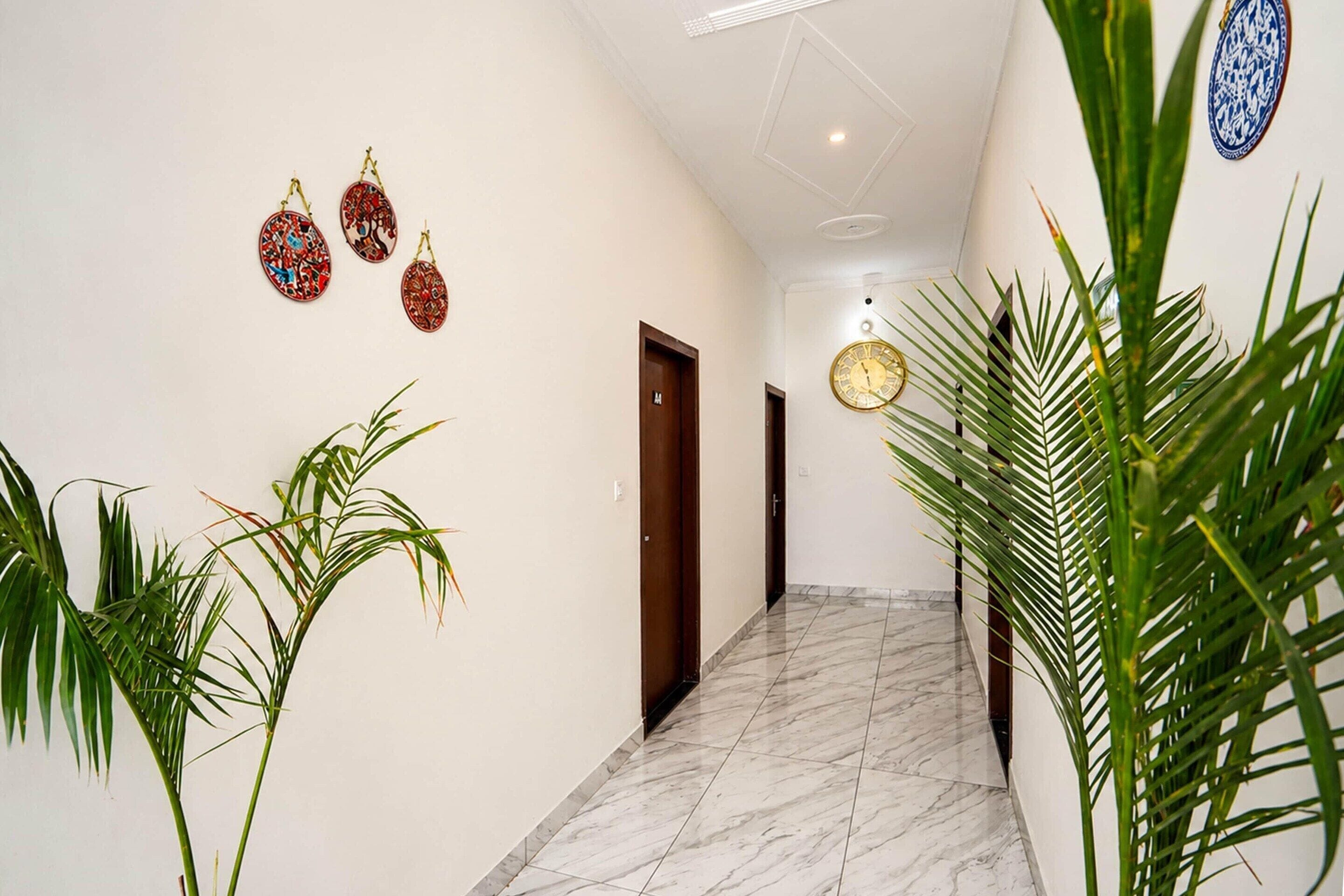 A hallway with a marble floor, a wooden door, and decorative wall hangings.