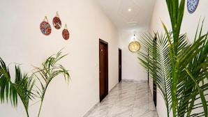 A hallway with a marble floor, a wooden door, and decorative wall hangings. - Collection O Salasar Balaji Temple (Sujangarh)