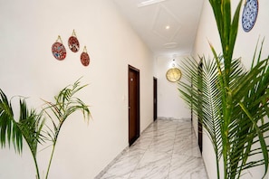 A hallway with a marble floor, a wooden door, and decorative wall hangings. - Collection O Salasar Balaji Temple (Sujangarh)