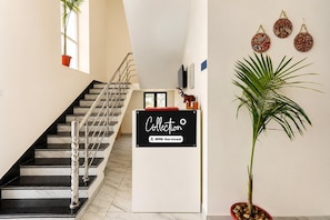 A staircase with a handrail, a sign reading 'Collection OYO-Serviced', and a potted plant. - Collection O Salasar Balaji Temple (Sujangarh)