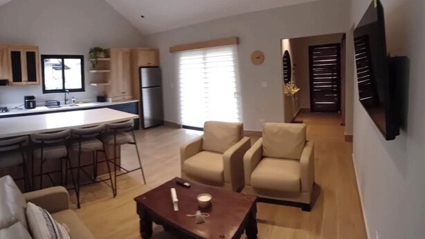 A modern living space with a kitchen, dining area, and seating area. - Boquete Cabins Retreat (Bajo Boquete)