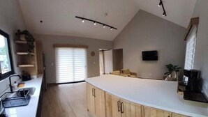 A modern kitchen with a central island, wooden cabinets, and a built-in oven. - Boquete Cabins Retreat (Bajo Boquete)