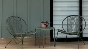 A patio area with two metal chairs and a small table, a potted plant, and a sliding door in the background. - Boquete Cabins Retreat (Bajo Boquete)