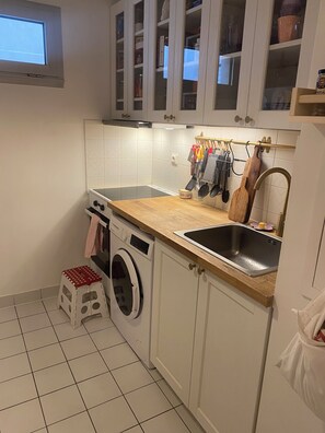 Une cuisine équipée d’un lave-linge, d’un évier et de placards.