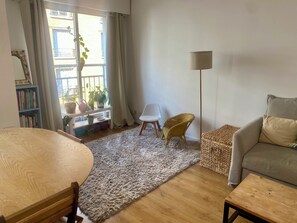 Un salon avec une table ronde, un canapé, un lampadaire et une bibliothèque.