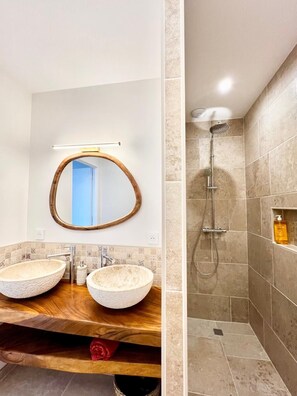 A bathroom with two round vessel sinks, a wooden vanity, a mirror with a wooden frame, and a shower area with beige tiles. - A cozy, quiet family home right in the heart of the city (Royan)