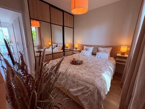 A modern bedroom with a large bed, bedside tables, a mirror, and a view of the outdoors. - A cozy, quiet family home right in the heart of the city (Royan)
