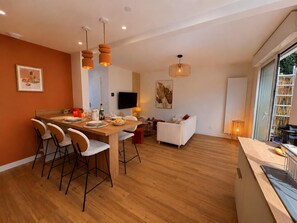 A modern kitchen with a dining area, a flat-screen TV, and a large window. - A cozy, quiet family home right in the heart of the city (Royan)