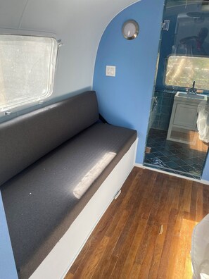 A compact interior with a bench, a small sink, and a window. - 1 BR 27’ Airstream with AC, WiFi, TV, in- and outdoor kitchens, pool, beach (Austin)