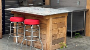 Una barra de madera con una encimera de metal y dos taburetes rojos.