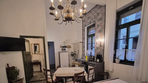 Una habitación acogedora con cama, mesa de comedor, kitchenette y un ventanal amplio.