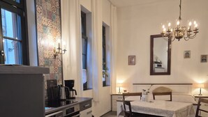 Una cocina compacta con electrodomésticos modernos, un comedor con una araña, y un espejo grande en la pared.