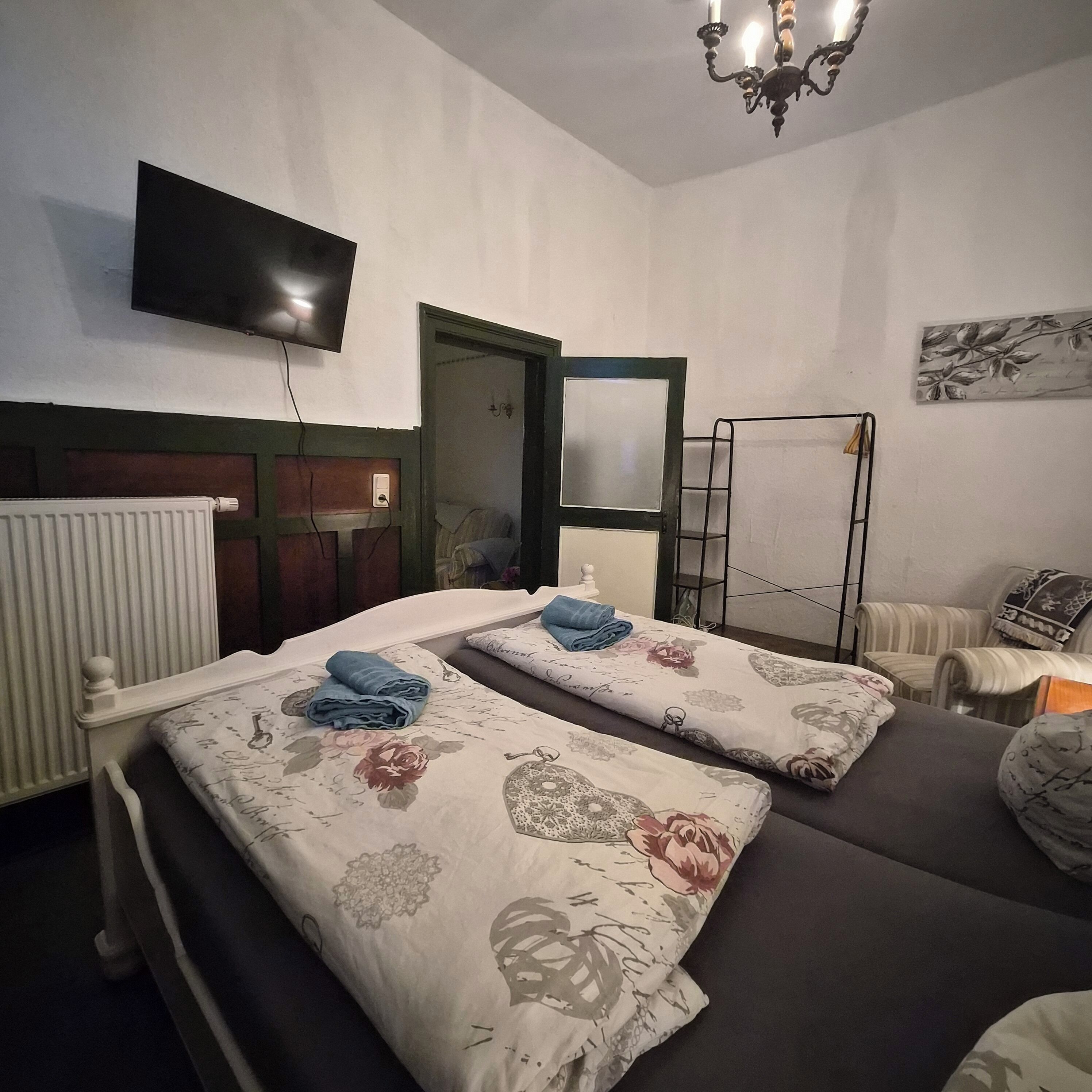 Un dormitorio con dos camas, un radiador, un televisor y una puerta.