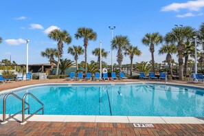 Ein Swimmingpool mit blauem Wasser, umgeben von Palmen und blauen Liegestühlen.