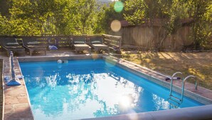Una piscina rectangular amb una escala a un costat, envoltada per un solàrium de fusta amb gandules.