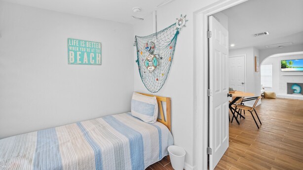 Une chambre à coucher avec un lit, un élément de décoration murale, une porte donnant sur une autre pièce et un téléviseur en arrière-plan.