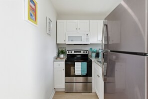 A compact kitchen with white cabinets, a stainless steel refrigerator, a microwave, and an oven. - ABC Private triplex near the beach and 5 ave South 6-bedroom 3-bath in Bayshore (Naples)