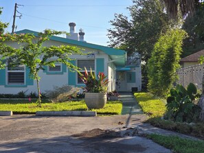 A single-story building with a green roof, a front porch, and a large planter with flowers. - ABC Private triplex near the beach and 5 ave South 6-bedroom 3-bath in Bayshore (Naples)