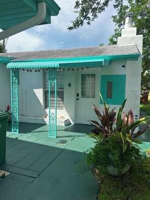 A building with a white facade and teal accents, a covered entrance, and a small garden area with plants. - ABC Private triplex near the beach and 5 ave South 6-bedroom 3-bath in Bayshore (Naples)