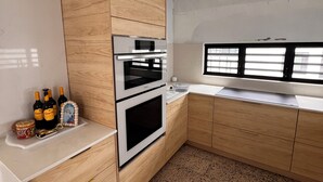 Una cuina moderna amb armaris de fusta, electrodomèstics d'acer inoxidable i un paviment amb motius.