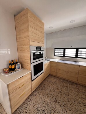 Eine moderne Küche mit Holzschränken, Edelstahlgeräten und einem punktierten Boden.