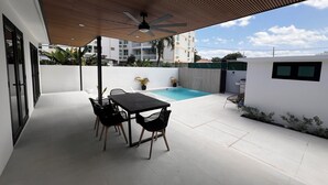 Terrassa exterior amb piscina, taula i cadires.