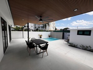 Eine Terrasse im Freien mit Pool, Tisch und Stühlen.