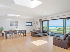Una sala moderna con comedor, un sofá y vista al mar.