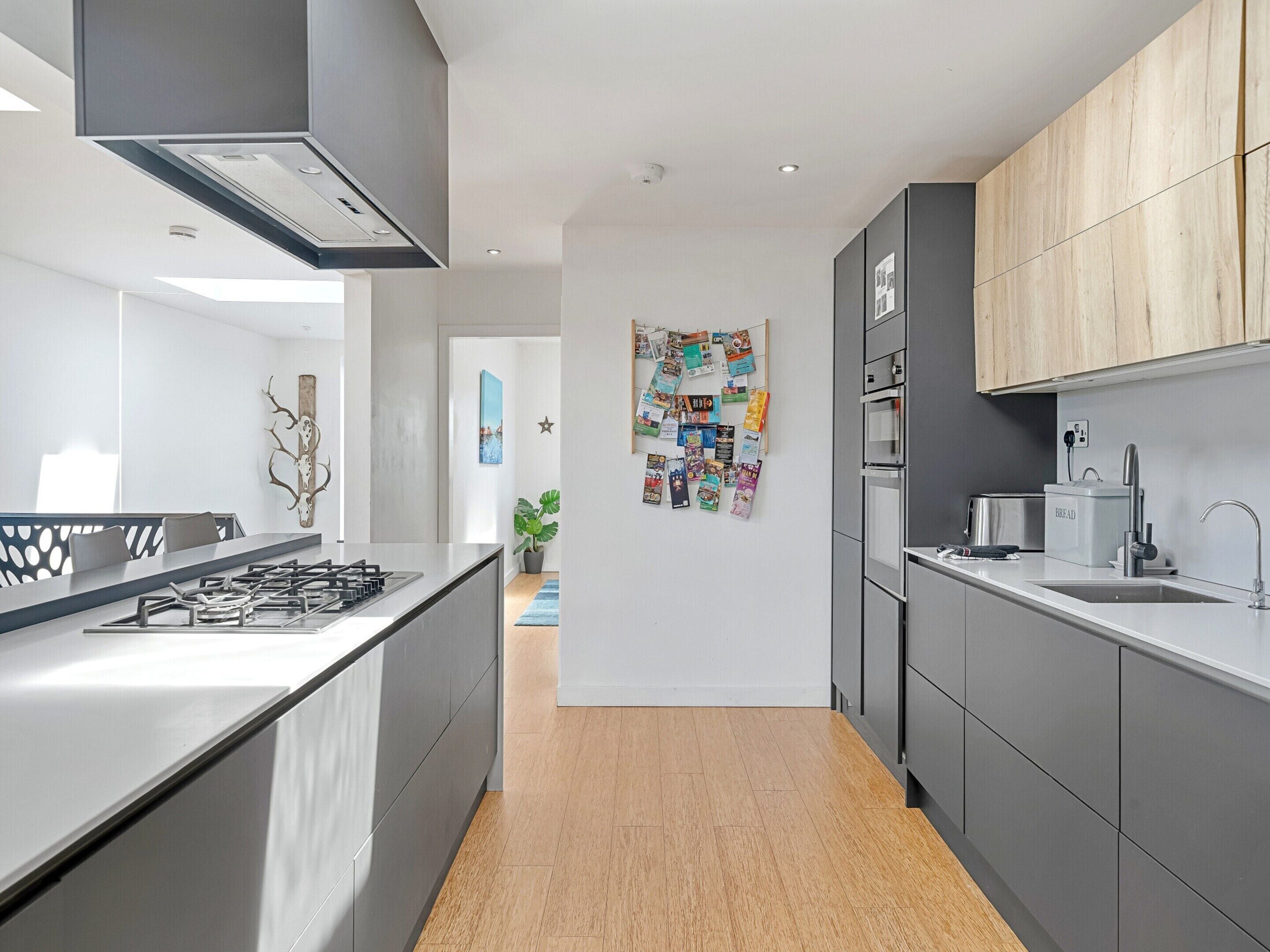 A modern kitchen with a central island, grey cabinetry, and a wooden accent wall.