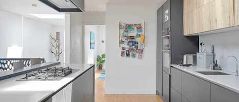 A modern kitchen with a central island, grey cabinetry, and a wooden accent wall.