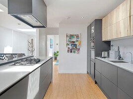 Una cocina moderna con una isla central, muebles grises y una pared de acento de madera.
