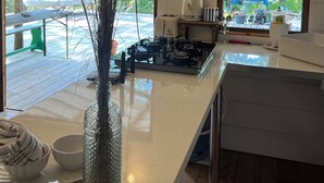 A modern kitchen with a central island, a stove, and a window overlooking a deck.